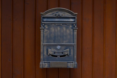 Photo of Metal letter box on wooden wall outdoors