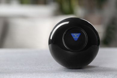 Photo of Magic eight ball with prediction Consult Me Later on light gray table, closeup. Space for text
