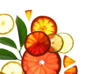 Illuminated slices of citrus fruits and leaves on white background, top view