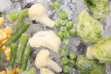 Different frozen vegetables on ice, flat lay