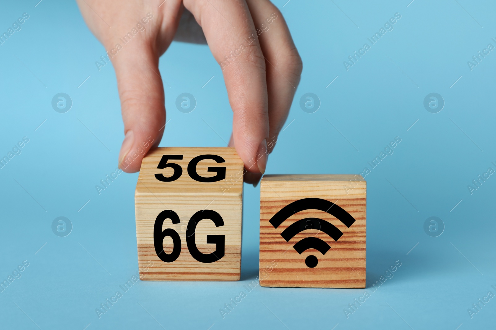 Photo of Man turning cube with 6G and 5G symbols near WiFi sign on light blue background, closeup