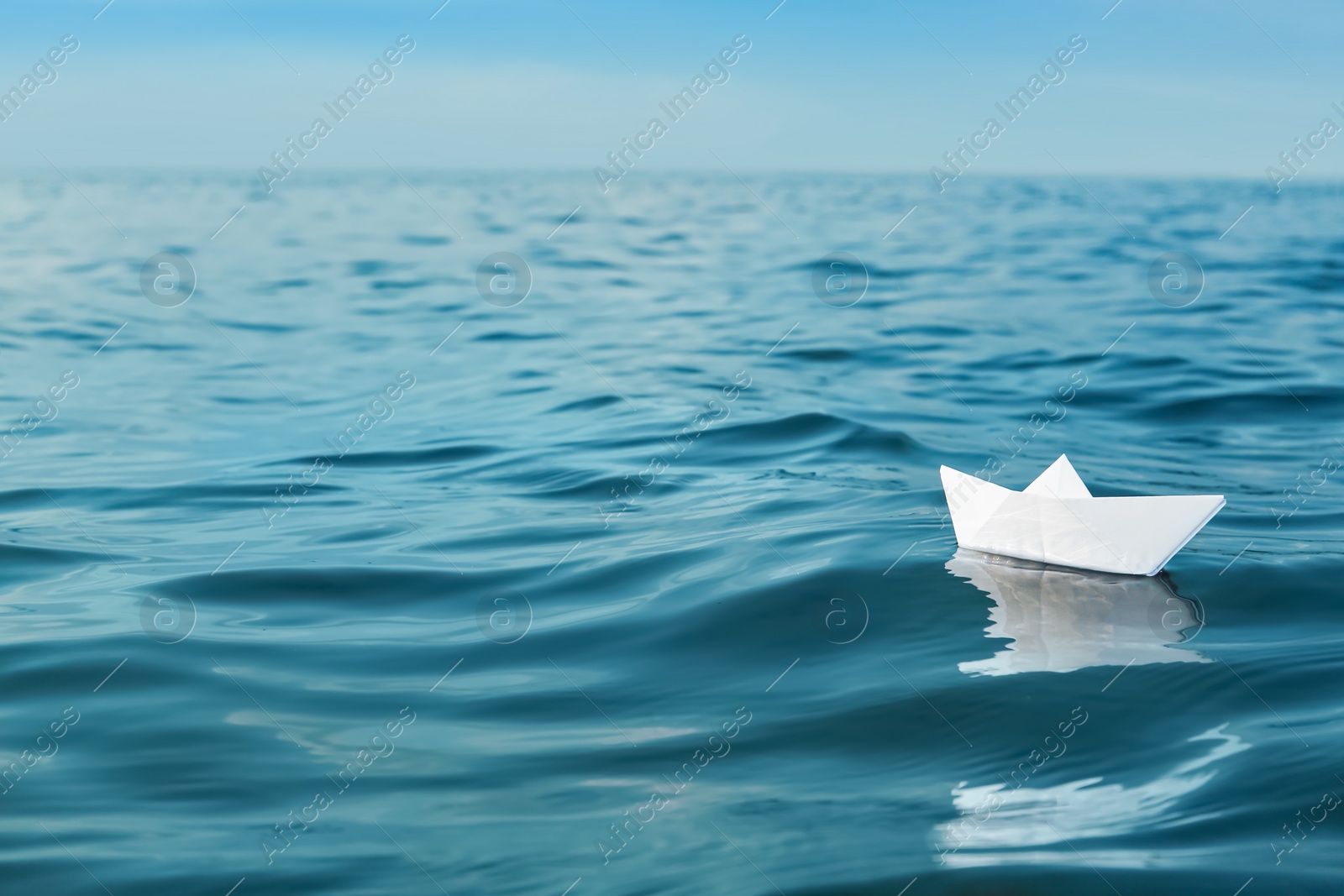 Photo of White paper boat floating on river, space for text