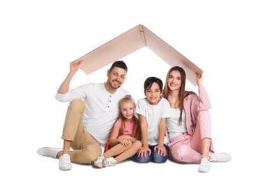 Photo of Happy family sitting under cardboard roof on white background. Insurance concept