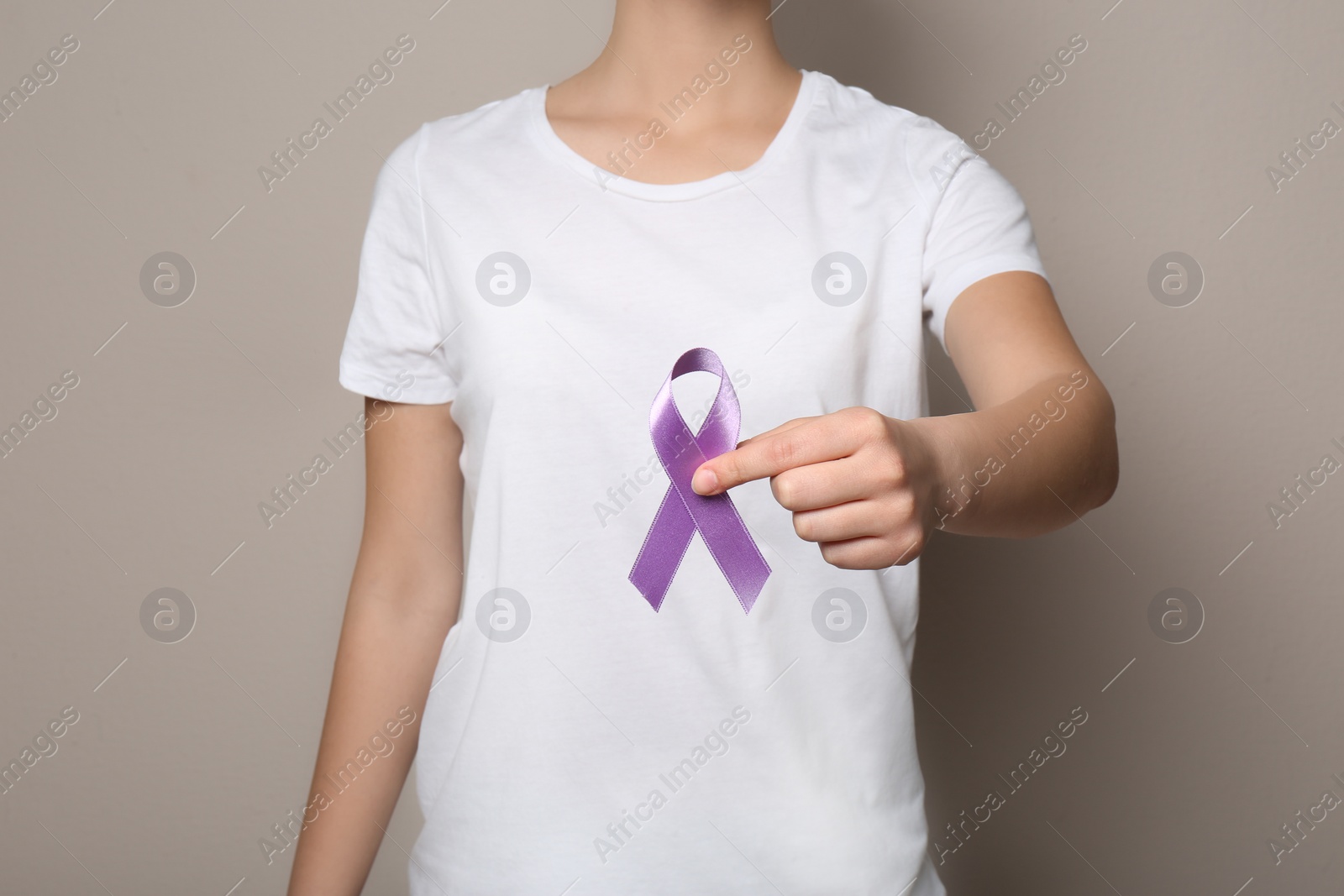 Photo of Woman holding purple ribbon on grey background, closeup. Domestic violence awareness