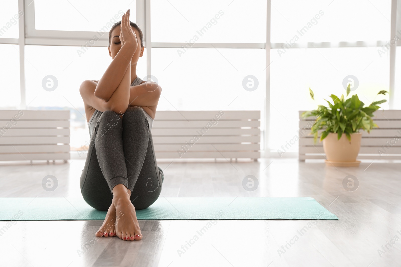 Photo of Young woman practicing eagle asana in yoga studio. Garudasana pose