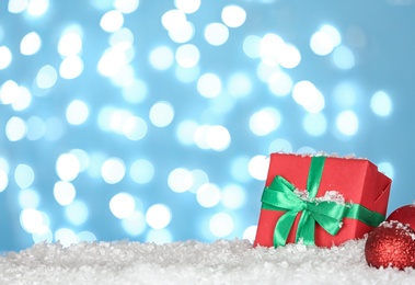 Photo of Christmas decoration and gift box on snow against blue background