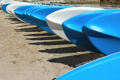 Photo of Many white and blue kayaks on sand near sea