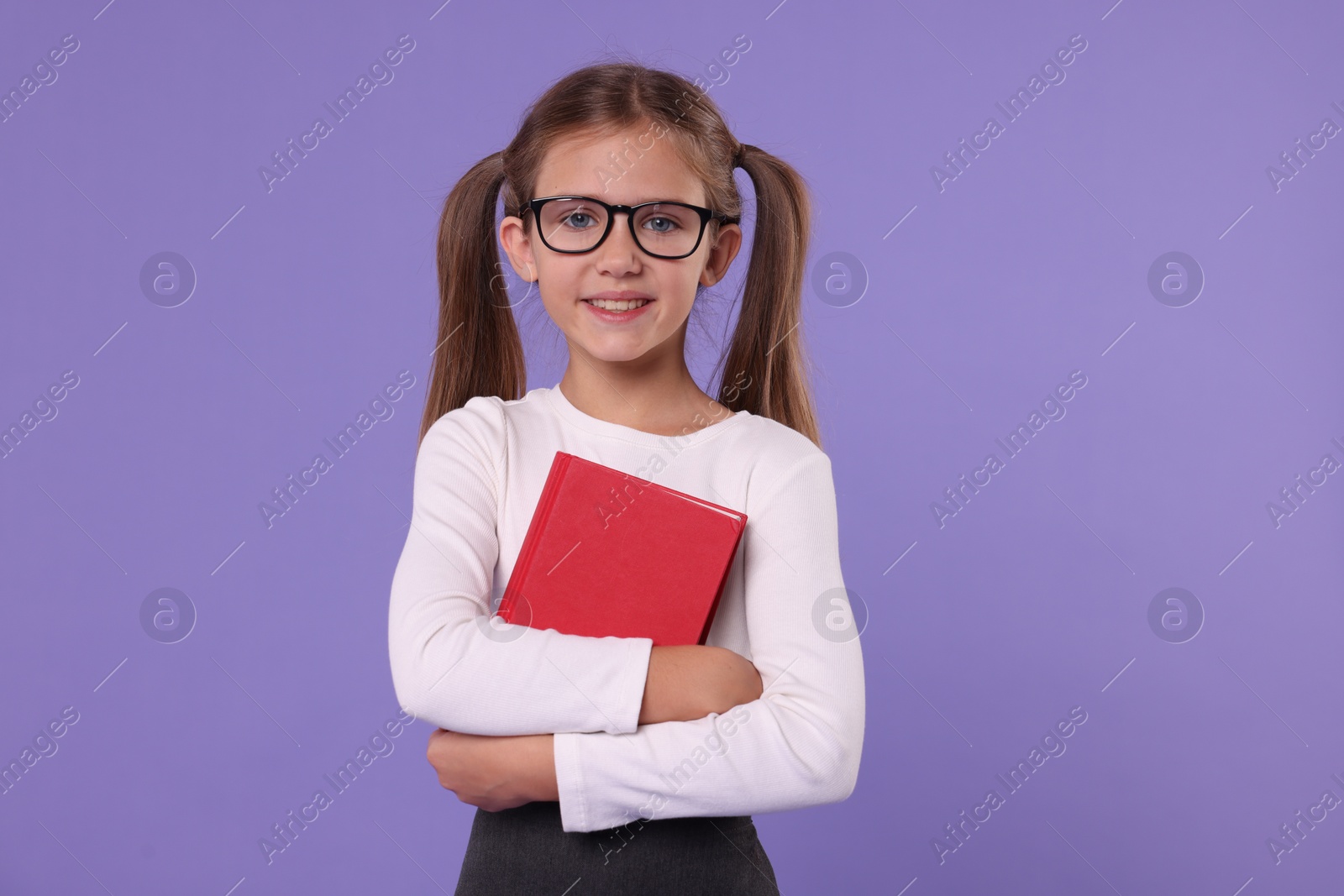 Photo of Smiling schoolgirl with book on violet background