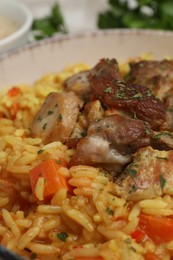 Delicious pilaf with meat in white bowl, closeup