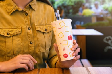 MYKOLAIV, UKRAINE - AUGUST 11, 2021: Woman with cold McDonald's drink in outdoor cafe, closeup