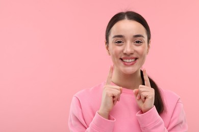 Photo of Beautiful woman showing her clean teeth and smiling on pink background, space for text