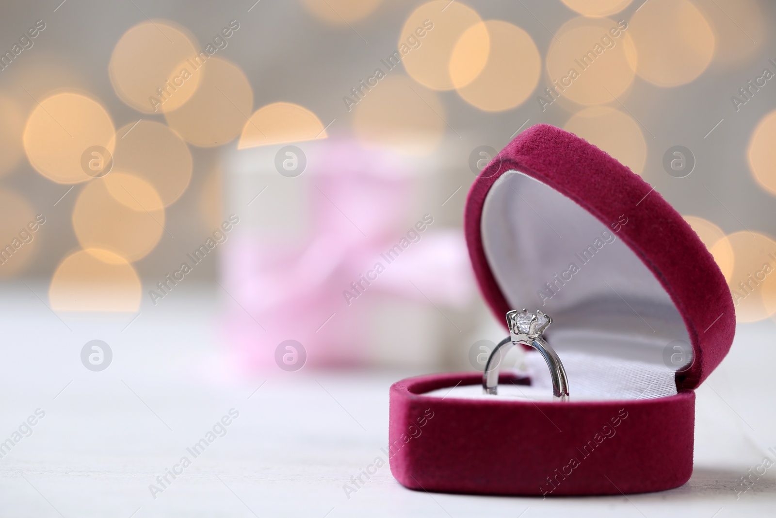 Photo of Box with ring on table against blurred lights. Space for text