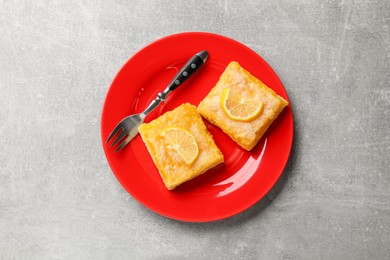 Photo of Tasty lemon bars and fork on light grey table, top view