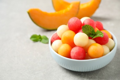 Photo of Melon balls and mint in bowl on grey table. Space for text