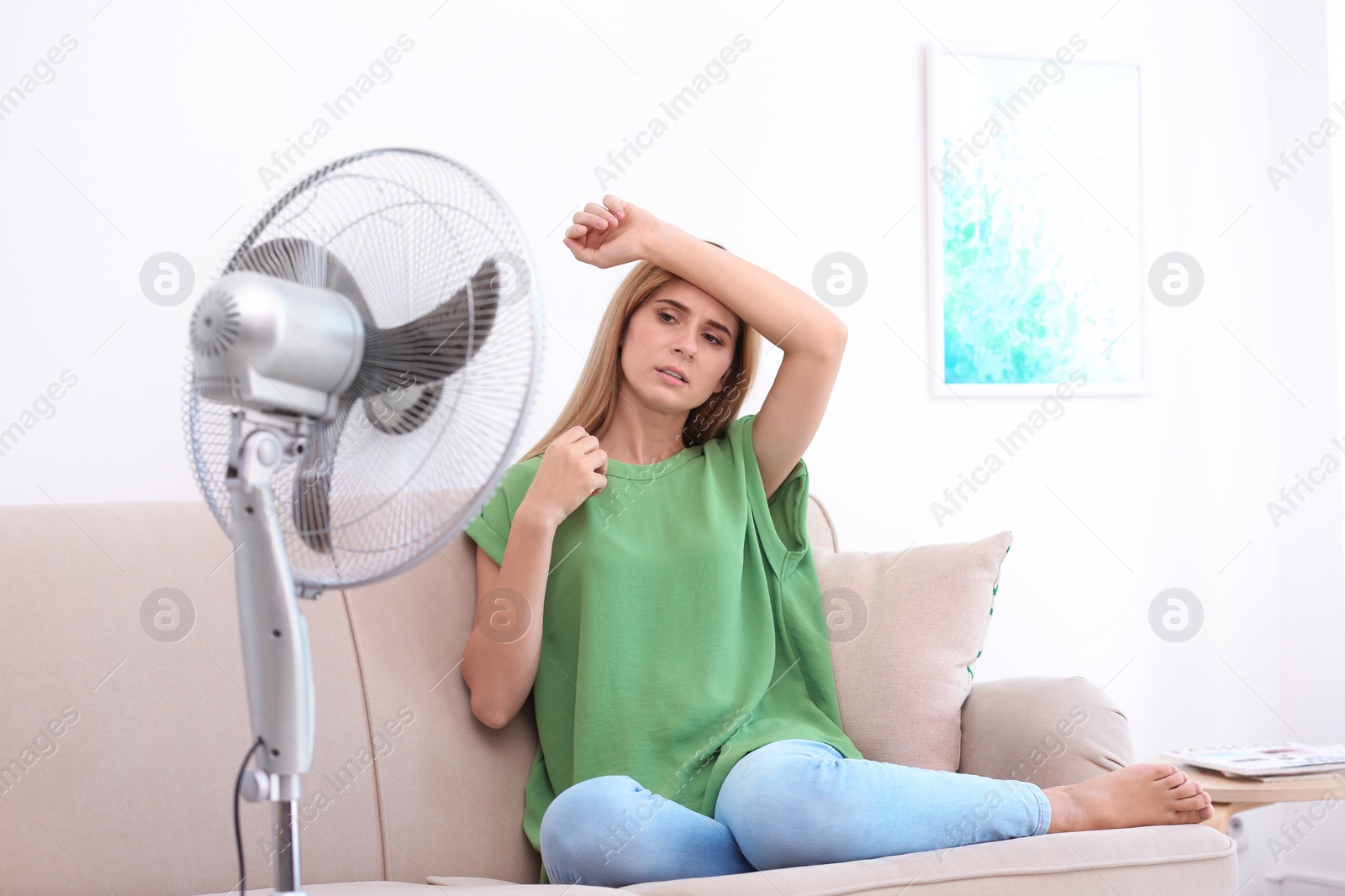 Photo of Woman suffering from heat in front of fan at home