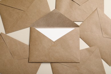 Photo of Many brown paper envelopes on beige background, flat lay