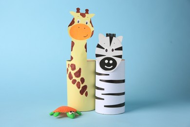 Photo of Toy giraffe and zebra made from toilet paper hubs with plasticine turtle on light blue background. Children's handmade ideas