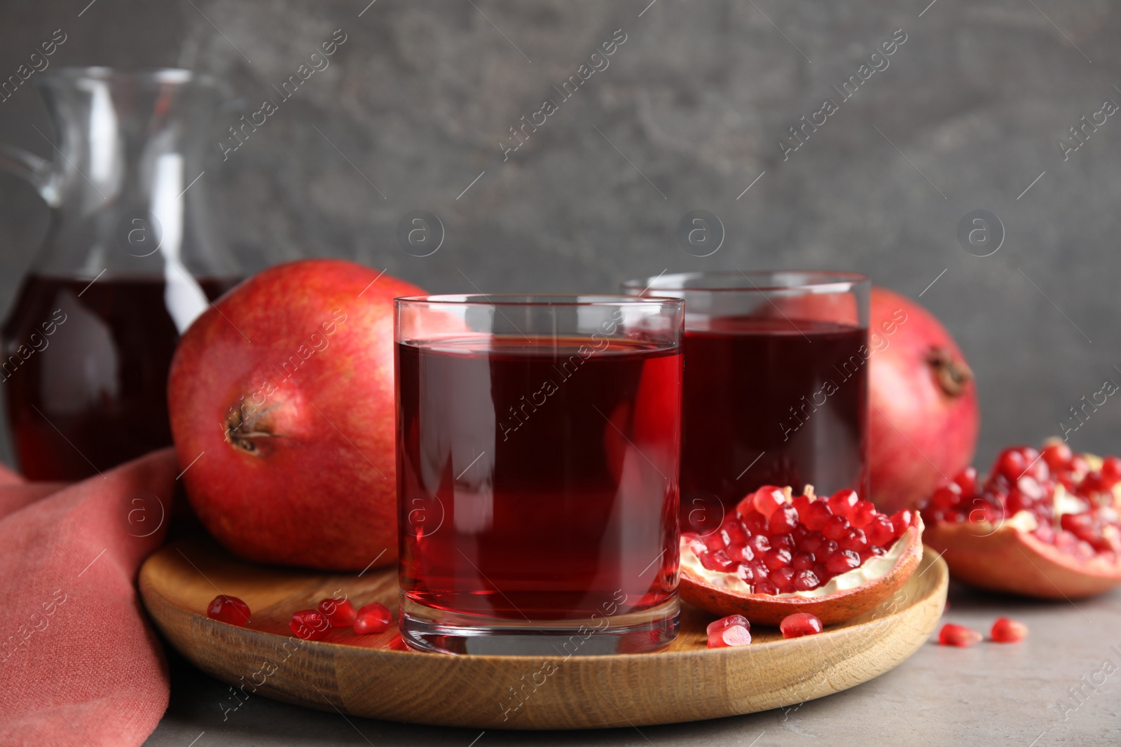Photo of Pomegranate juice and fresh fruits on grey table