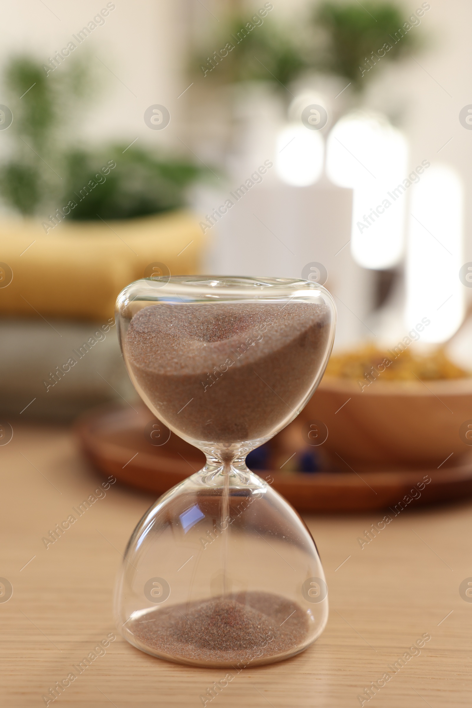 Photo of Sandglass on wooden table indoors. Spa time