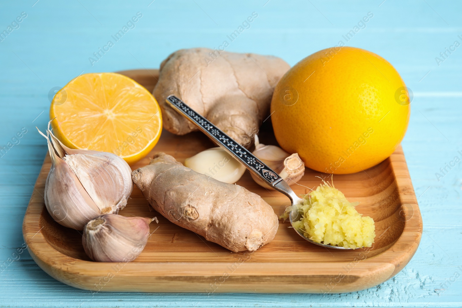 Photo of Fresh garlic and other natural cold remedies on light blue wooden table