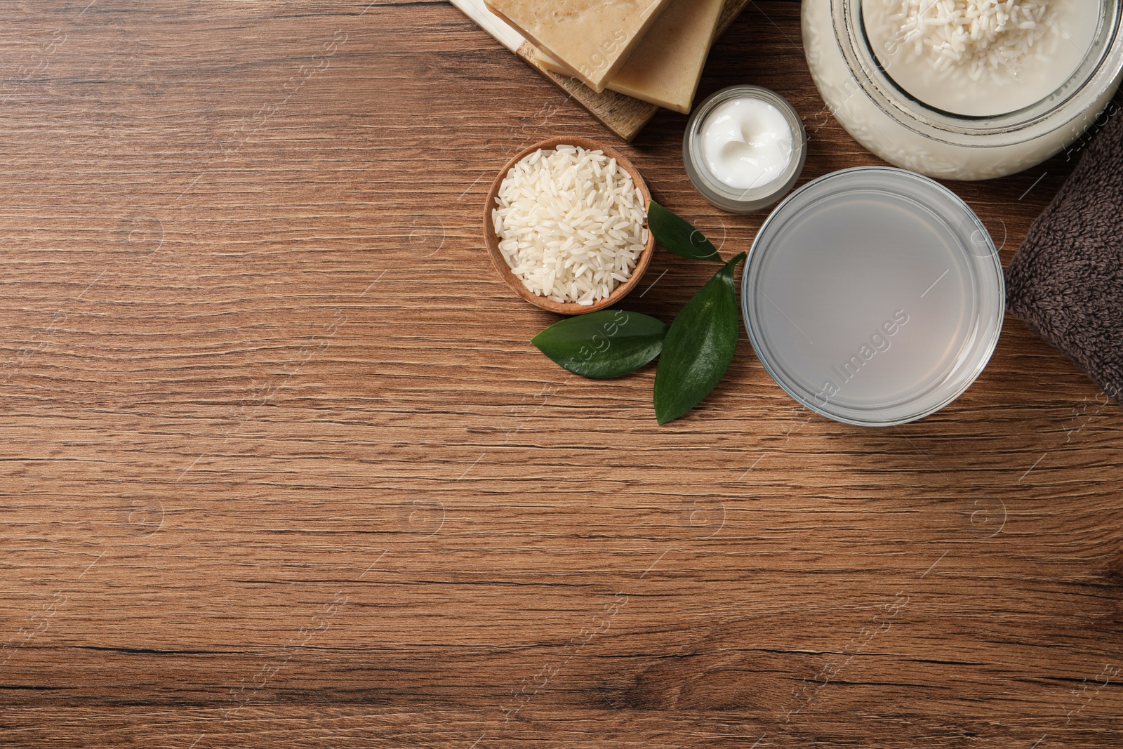 Photo of Homemade natural rice water and cosmetic products on wooden table, flat lay. Space for text