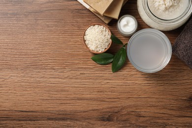 Photo of Homemade natural rice water and cosmetic products on wooden table, flat lay. Space for text