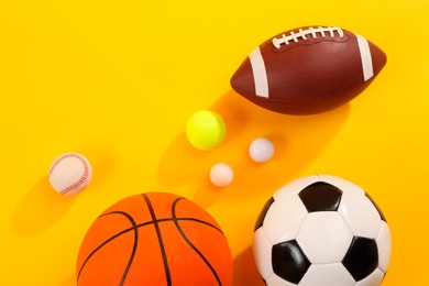 Many different sports balls on yellow background, flat lay