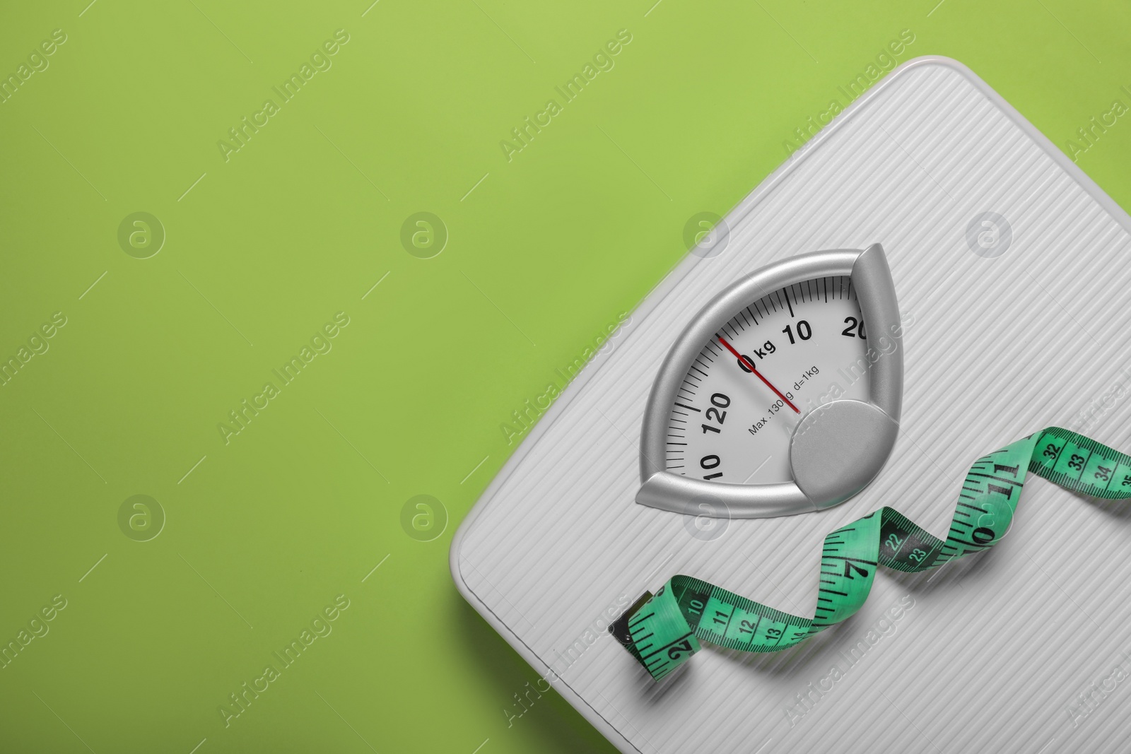 Photo of Weight loss concept. Scales and measuring tape on green background, top view. Space for text