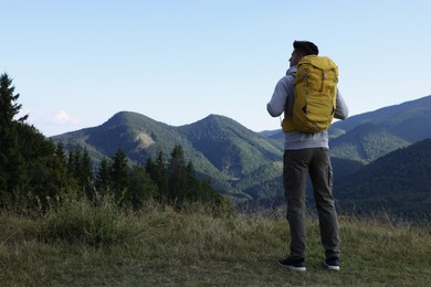 Tourist with backpack enjoying mountain landscape, back view. Space for text