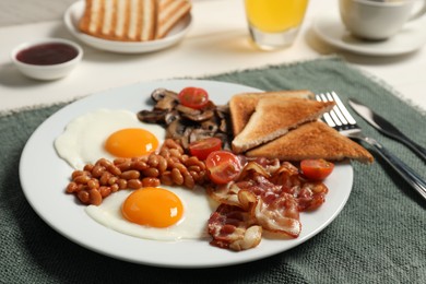 Photo of Plate with fried eggs, mushrooms, beans, tomatoes, bacon and toasts served on table, closeup. Traditional English breakfast