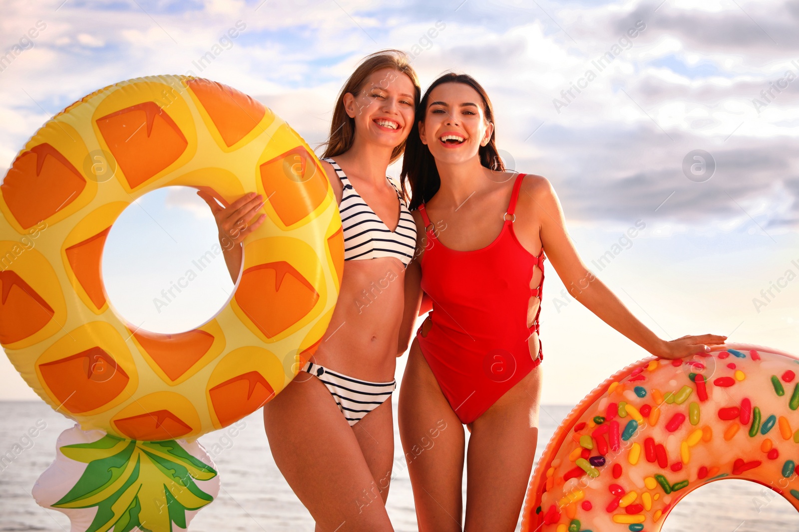 Photo of Young woman in bikini with girlfriend on beach. Lovely couple