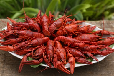 Photo of Plate with delicious red boiled crayfish on wooden table