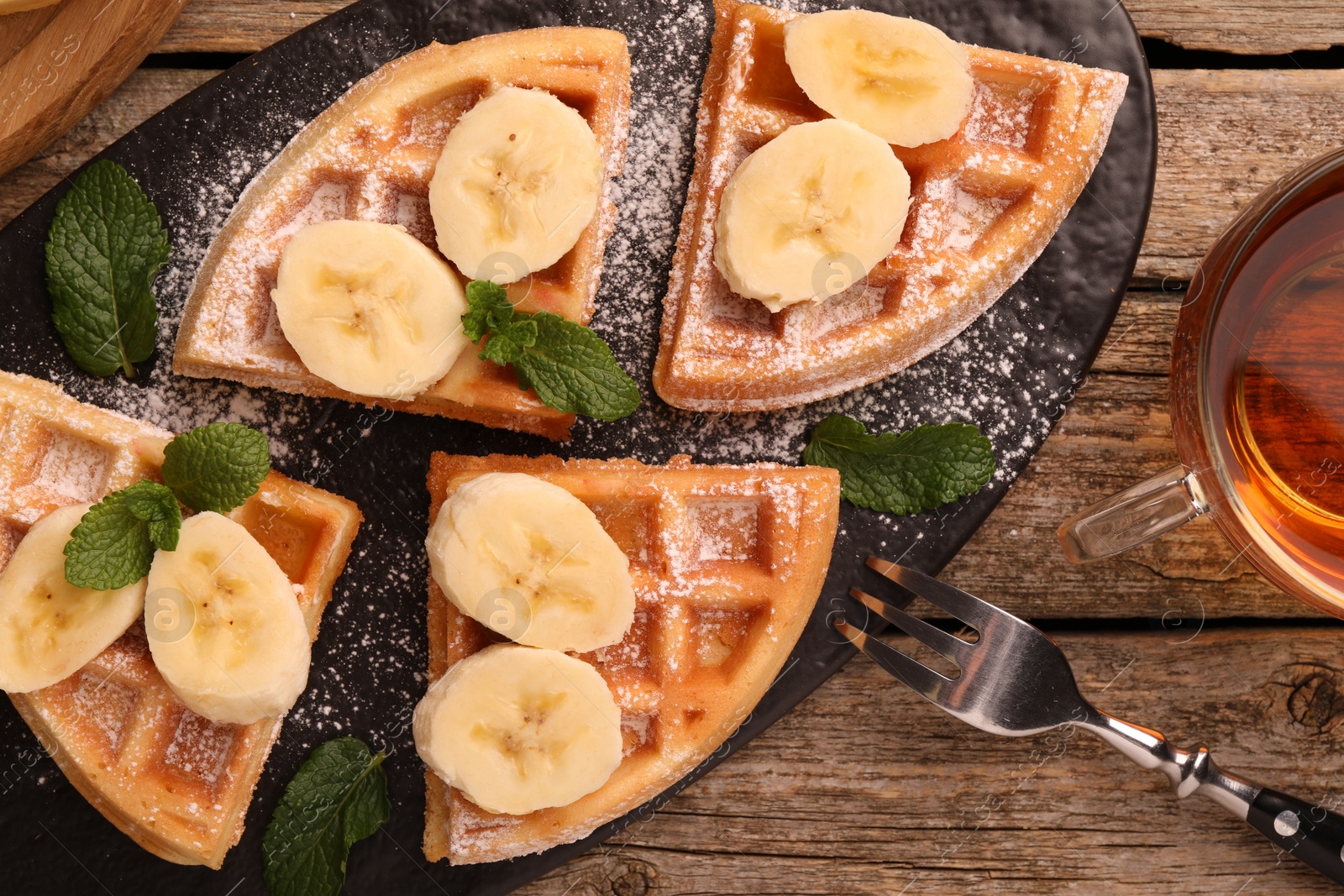 Photo of Tasty Belgian waffles with banana, mint and fork on wooden table, flat lay