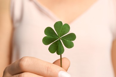 Photo of Woman holding green four leaf clover in hand, closeup