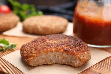 Photo of Delicious bitten vegan cutlet on wooden board, closeup