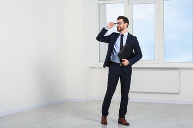 Photo of Handsome real estate agent with documents in empty room, space for text
