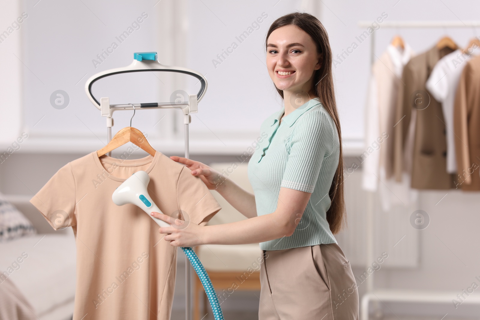 Photo of Woman steaming shirt on hanger at home