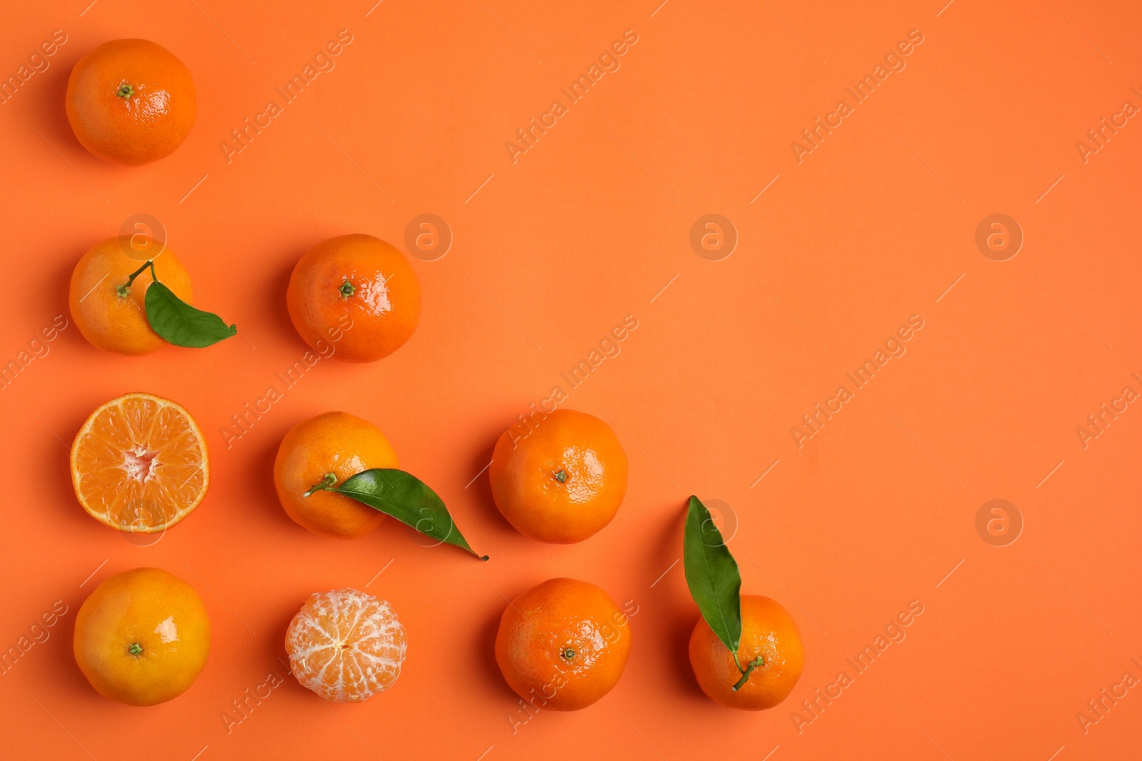 Photo of Delicious tangerines and green leaves on orange background, flat lay. Space for text