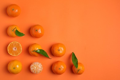 Photo of Delicious tangerines and green leaves on orange background, flat lay. Space for text