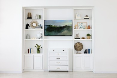 Photo of Interior design. Stylish tv area, chest of drawers and shelves with accessories indoors
