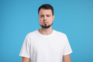 Portrait of sad man on light blue background