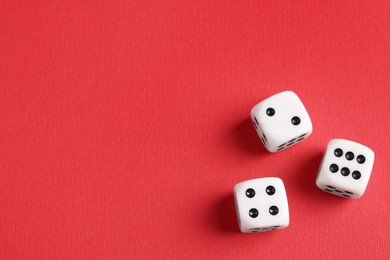 Three white game dices on red background, flat lay. Space for text