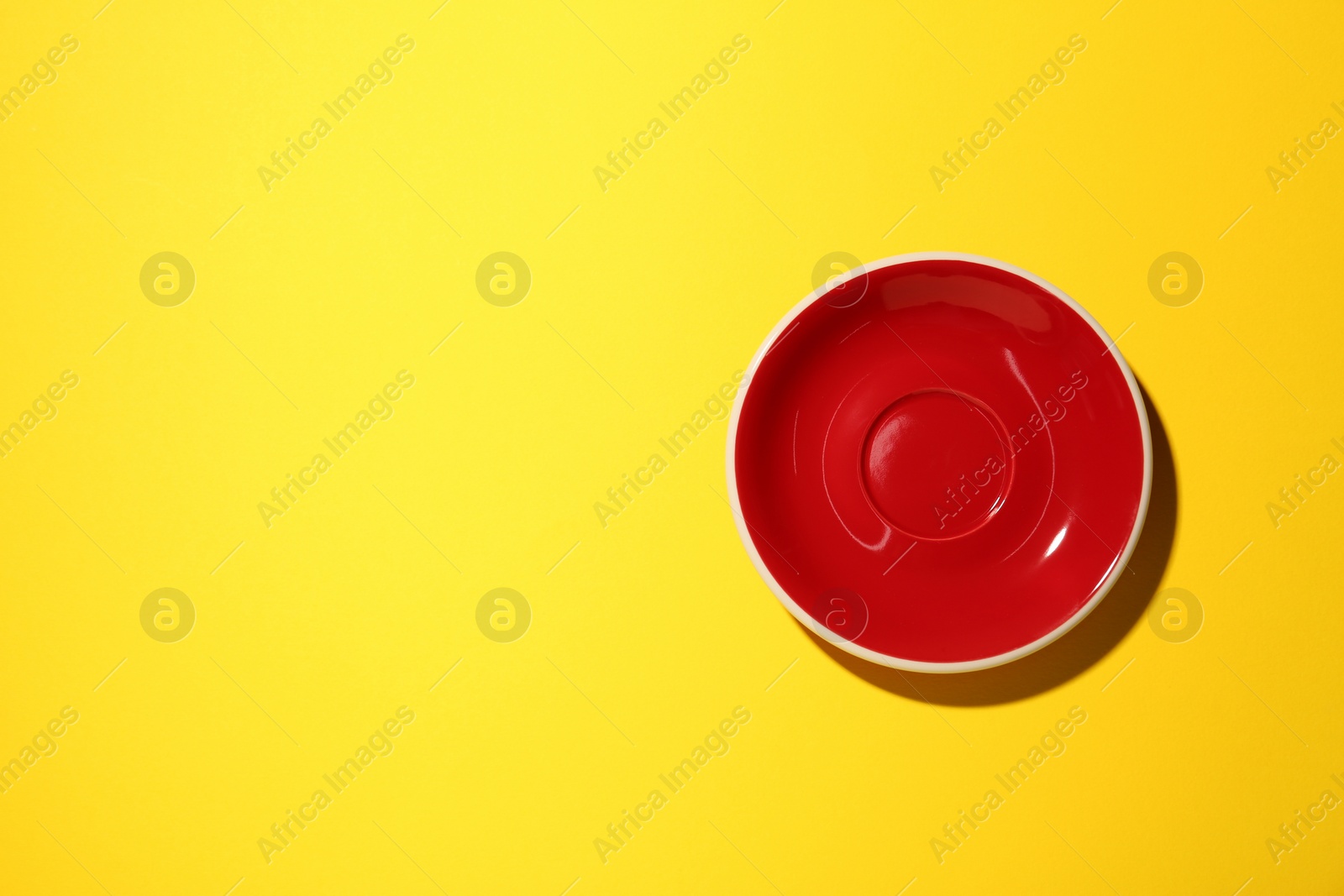 Photo of One clean plate on yellow background, top view with space for text. Ceramic dinnerware