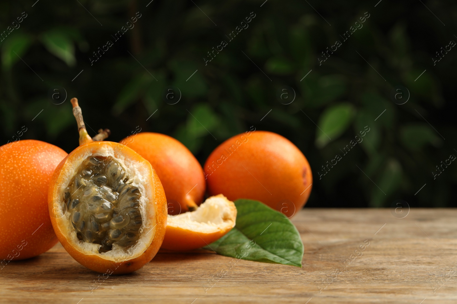 Photo of Delicious ripe granadillas on wooden table, space for text