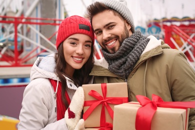 Photo of Lovely couple with Christmas presents in amusement park