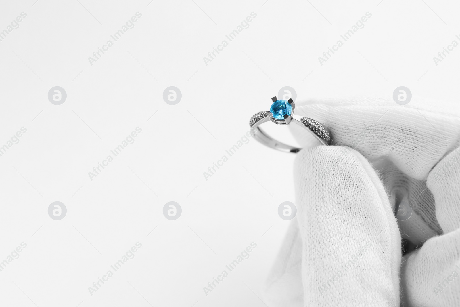 Photo of Jeweler holding topaz ring on white background, closeup. Space for text