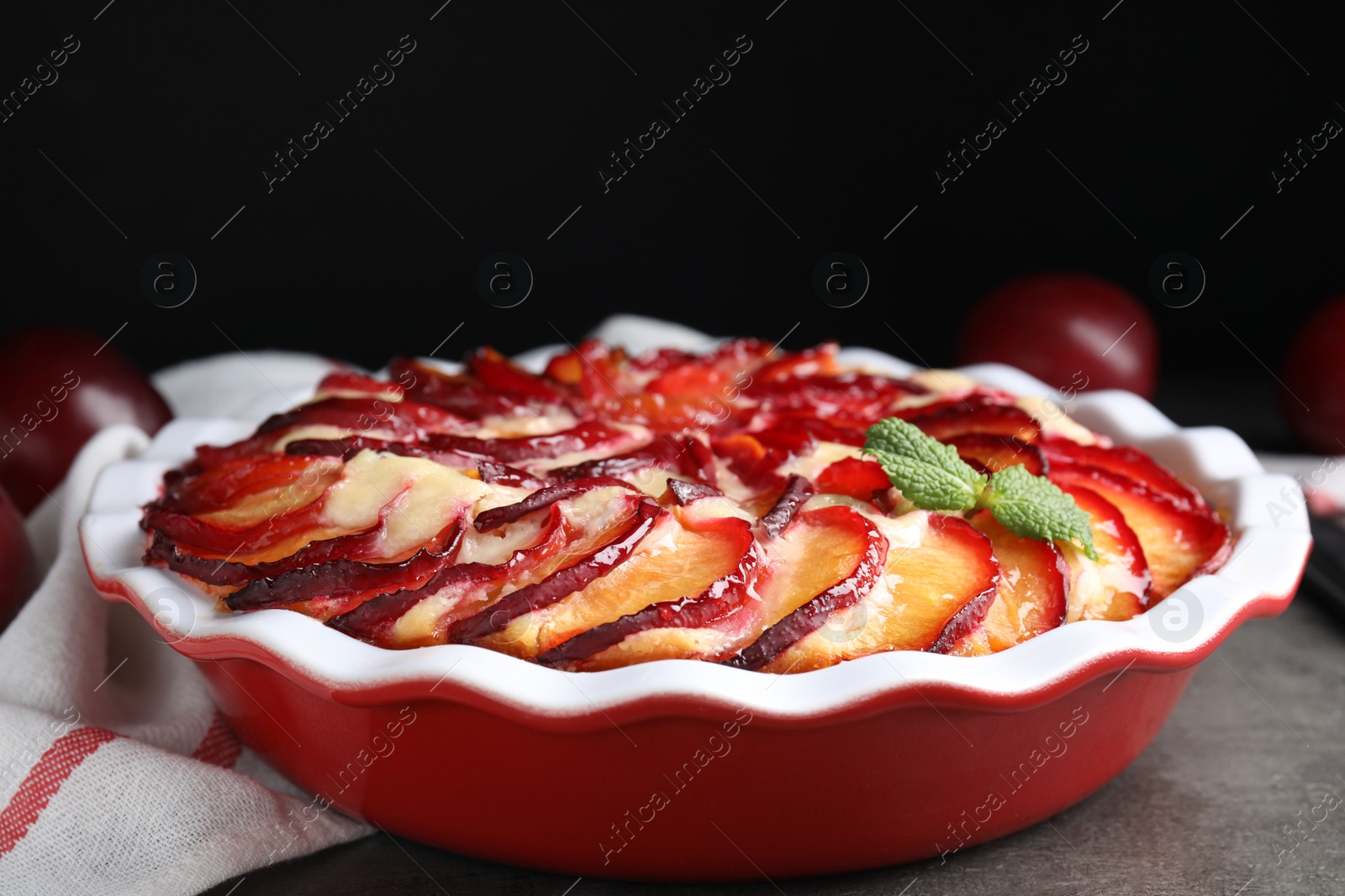 Photo of Delicious cake with plums on grey table, closeup