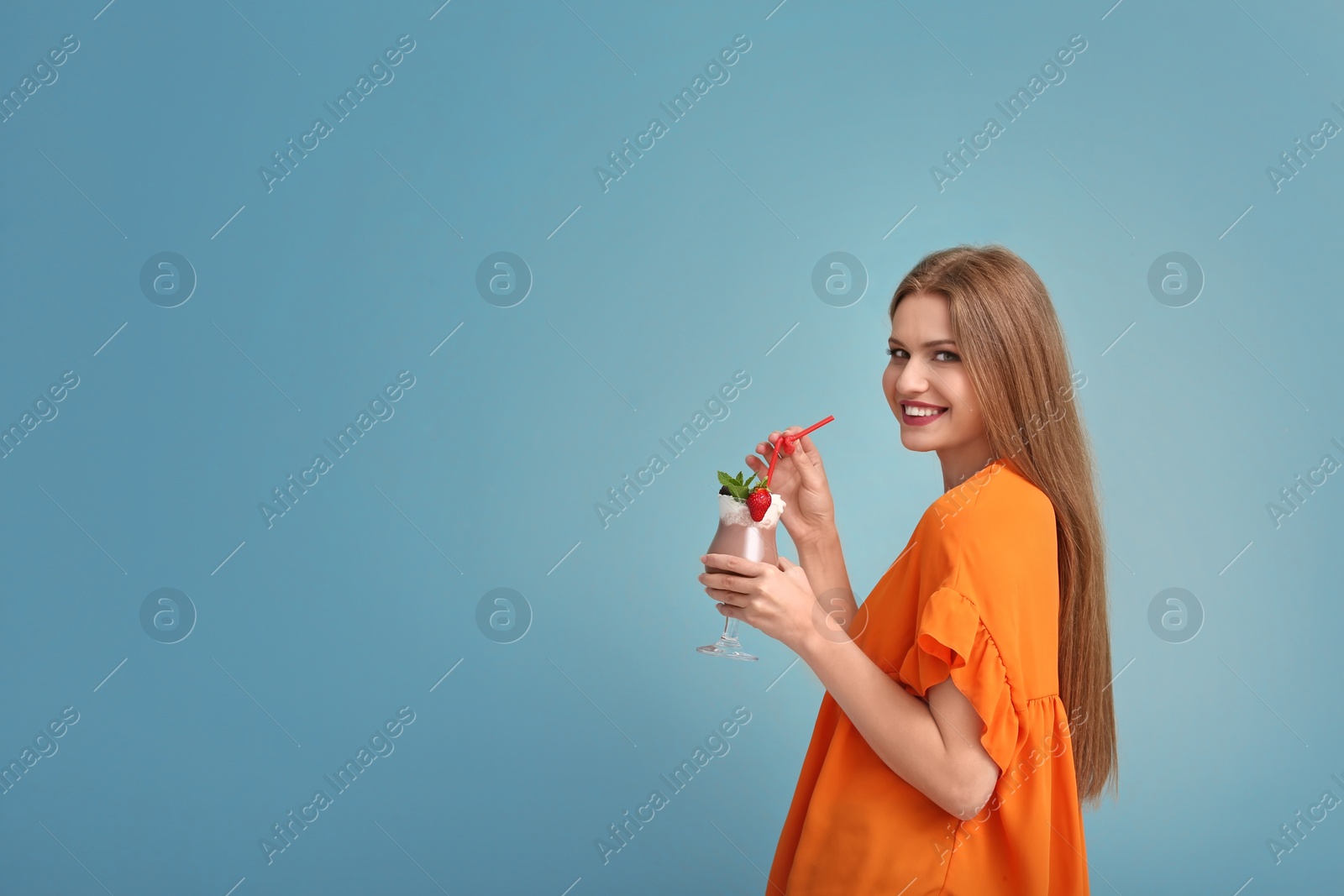 Photo of Young woman with glass of delicious milk shake on color background