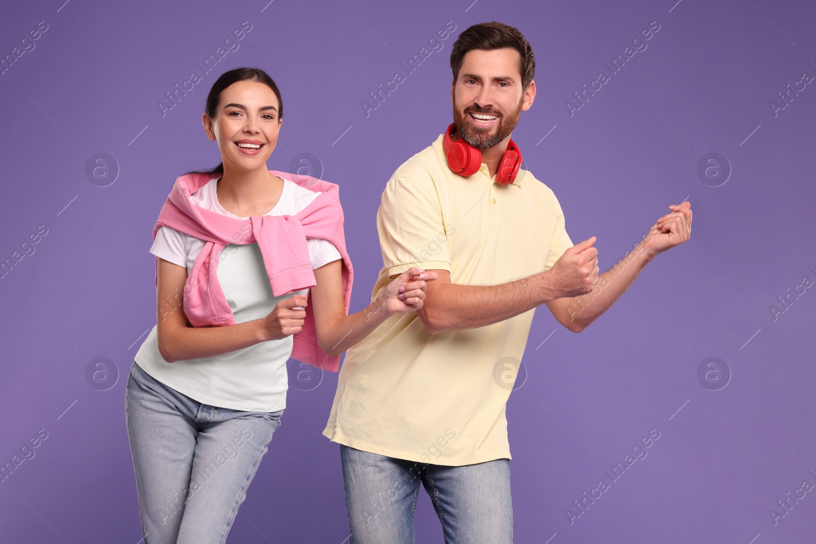 Photo of Happy couple dancing together on violet background