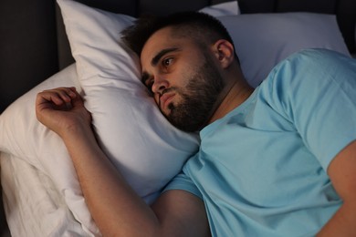 Photo of Frustrated man suffering from insomnia on bed